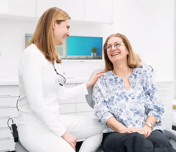 Zahnärztin sitzt neben einer Patientin und bespricht den Behandlungsplan
